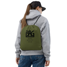 Load image into Gallery viewer, Person wearing a green drawstring bag with B,A,G Logo combined with &#39;Basic Activity Gear&#39; text on it
