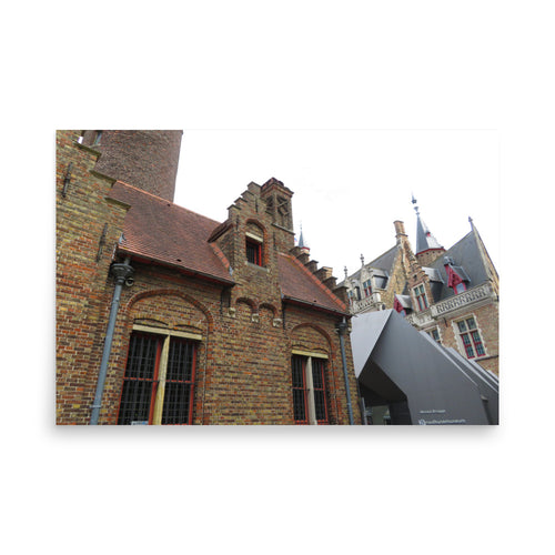 Brick building with modern grey accent and another building with a pointed roof in the background.