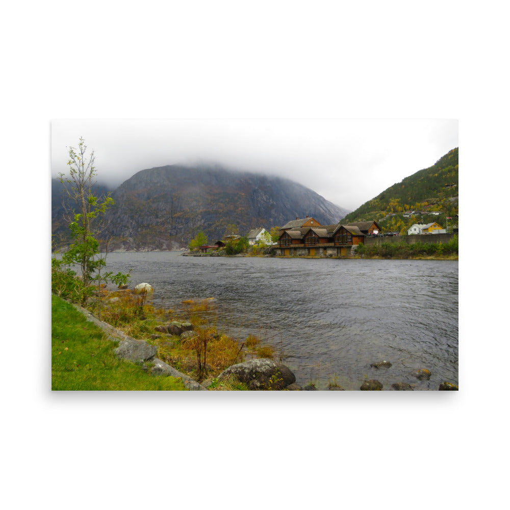 Scenic view of a lake with mountains and traditional wooden houses.